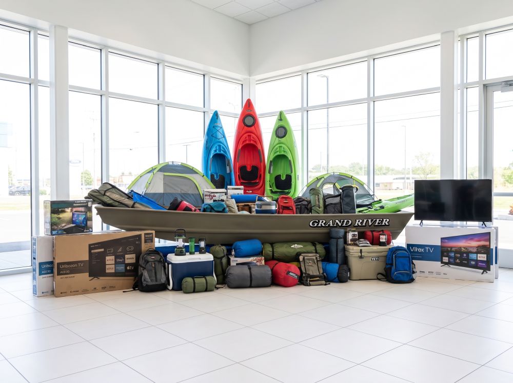 Prize Mountain giveaway display with kayaks, camping gear, a Jon boat, TVs, and outdoor equipment